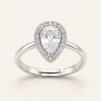 A pear-shaped diamond halo ring in silver-toned metal, featuring a large central pear-cut gemstone surrounded by a halo of smaller diamonds, with an adjustable split-band design, set against a solid off-white background.