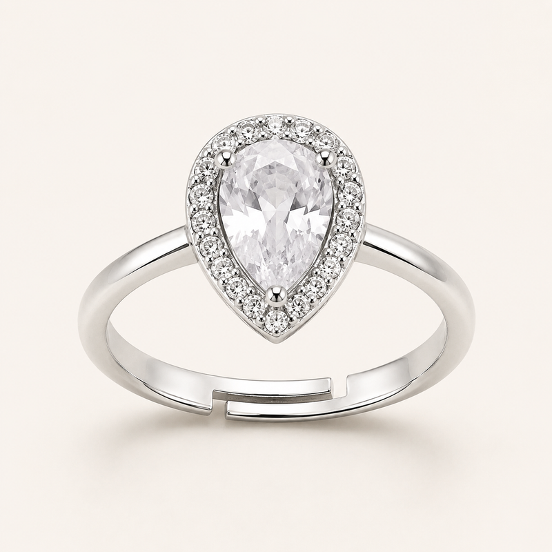 A pear-shaped diamond halo ring in silver-toned metal, featuring a large central pear-cut gemstone surrounded by a halo of smaller diamonds, with an adjustable split-band design, set against a solid off-white background.